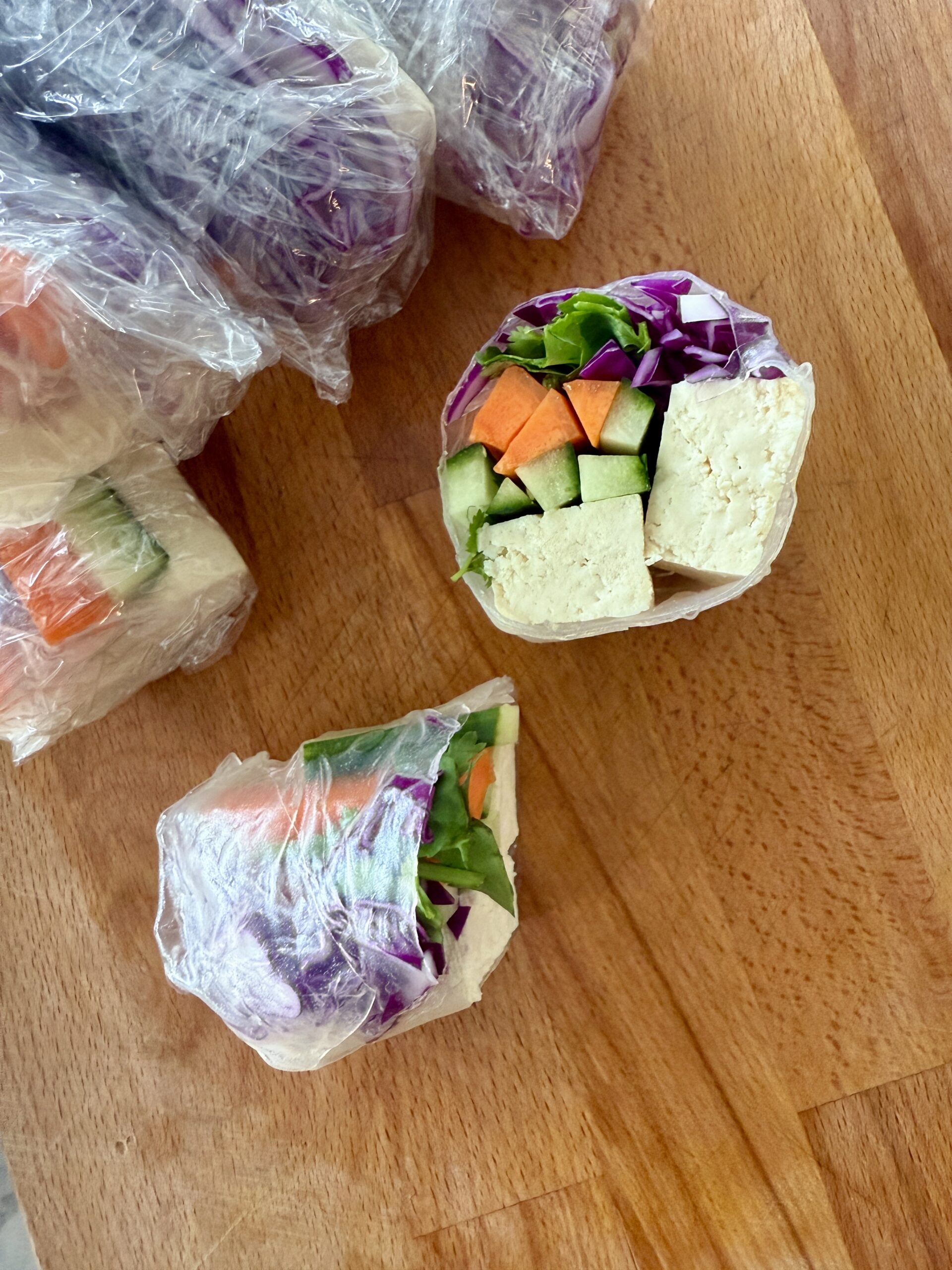 Tofu Spring Rolls with Creamy Peanut Dipping Sauce cover photo hand holding half of a spring roll